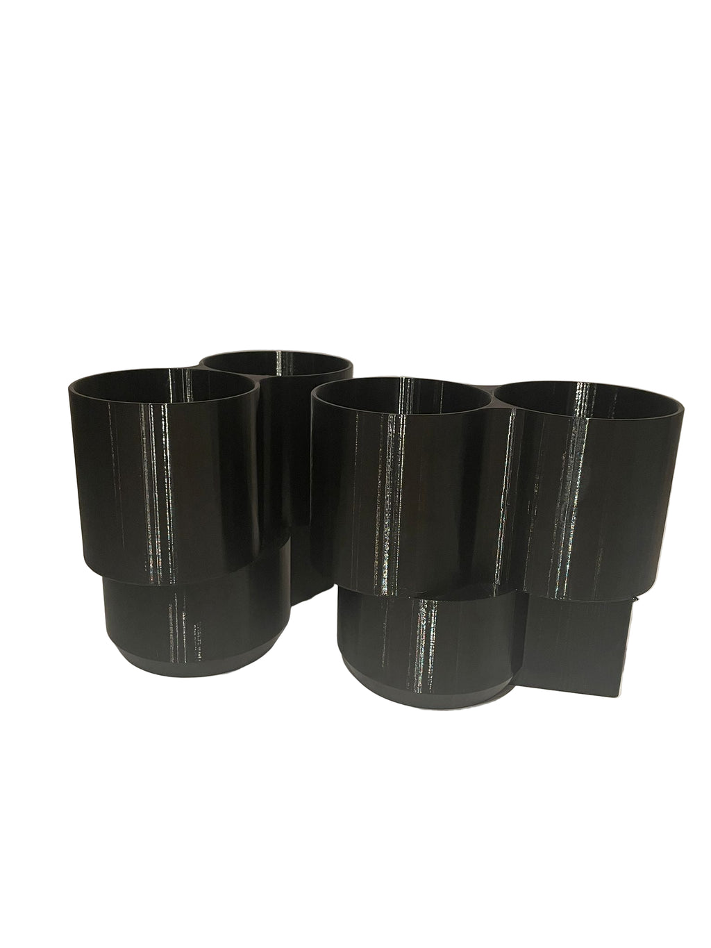 Four black cylindrical objects on a white surface with a neutral background